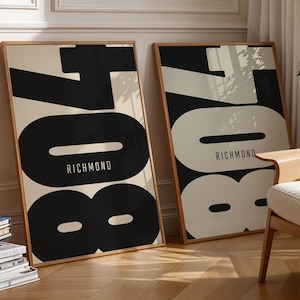 May include: Two framed art prints with the word "RICHMOND" and the number "708" in a bold, modern font. One print has a black design on a cream background, and the other has a cream design on a black background. The frames are a light wood color.