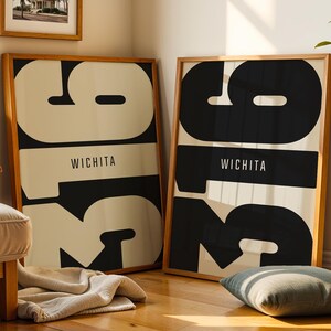May include: Two framed vertical posters in light wood frames, each featuring the large black numbers 316 and the word WICHITA in a clean sans-serif font. The design uses a bold contrast between black typography and a cream-colored background.