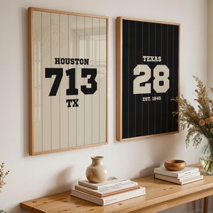 Puede incluir: Dos cuadros enmarcados. Uno muestra "HOUSTON 713 TX" en negro sobre fondo beige. El otro presenta "TEXAS 28 EST. 1845" en blanco sobre fondo negro. Ambos están en marcos de madera, para decoración.