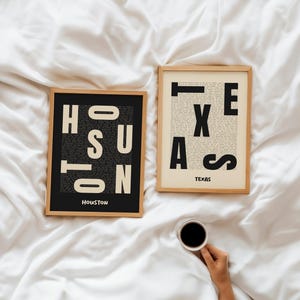 May include: Two framed prints with the words "HOUSTON" and "TEXAS" in bold letters. The "HOUSTON" print is on a black background, while the "TEXAS" print is on a vintage paper background. A hand holds a coffee cup.