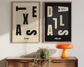 May include: Two framed art prints. One features the word "TEXAS" in large black letters over a beige background filled with text. The other print says "DALLAS" in large white letters over a black background filled with text. Both are in wooden frames.