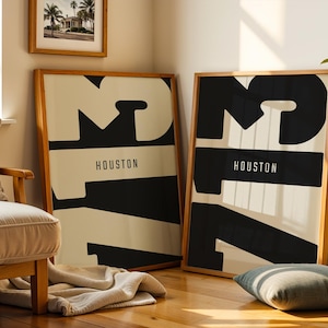 Puede incluir: Dos impresiones artísticas enmarcadas con un diseño minimalista. Cada impresión presenta un gran número 17 negro con la palabra "HOUSTON" en un rectángulo negro. El fondo es blanquecino y los marcos son de madera.