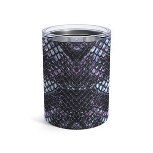 May include: A cylindrical tumbler with a stainless steel rim and lid. The exterior features a textured, iridescent pattern in shades of black, purple, and teal, resembling snakeskin. The tumbler is designed to hold beverages.