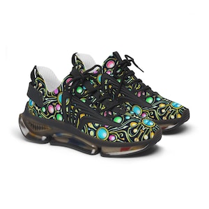 May include: Black trainers with a vibrant, abstract design of circles and swirls in blue, green, pink, and yellow. The trainers have black laces and a clear sole.