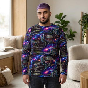 May include: A long-sleeve shirt with a vibrant, space-themed design. The shirt features a dark background with colorful nebulae, circuit board patterns, and lines of code. The design incorporates shades of blue, purple, and pink, creating a tech-inspired aesthetic.