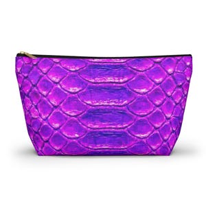 May include: A vibrant purple cosmetic bag with a snakeskin pattern. The bag features a gold zipper and a black trim. The design is a gradient of purple hues, creating a textured, scaly appearance. The bag is likely made of a durable, synthetic material.