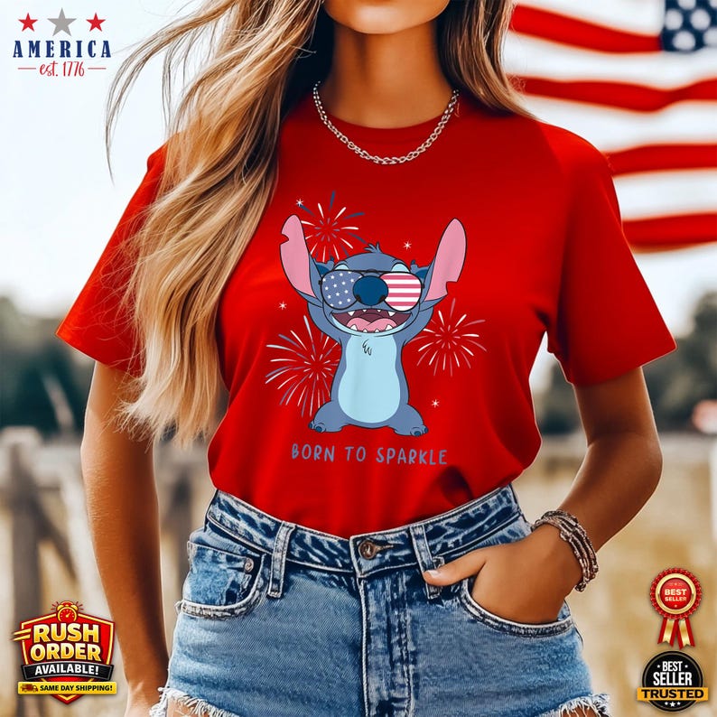 Puede incluir: Camiseta roja con un personaje de dibujos animados con gafas de sol con la bandera americana, con fuegos artificiales y el texto "BORN TO SPARKLE". La camiseta se combina con pantalones cortos de mezclilla. Temas patri&oacute;ticos.