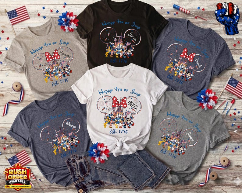以下が含まれることがあります： 様々な色のTシャツ。ミッキーマウスのデザイン、赤いリボン、そして「Happy 4th of July」の文字が特徴です。各シャツには名前と「Est. 1776」の日付が記載されています。アメリカの国旗と装飾が配置されています。