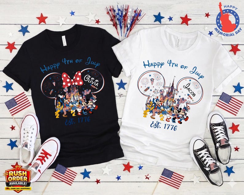 以下が含まれることがあります： 7月4日の愛国的なデザインの黒と白のTシャツ。花火、テキスト「Happy 4th of July」、年号「Est. 1776」が特徴のディズニーをテーマにしたグラフィックがプリントされています。