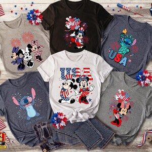 Puede incluir: Colecci&oacute;n de camisetas gr&aacute;ficas patri&oacute;ticas con personajes de Disney. Los dise&ntilde;os incluyen a Mickey y Minnie Mouse en rojo, blanco y azul, Stitch con la Estatua de la Libertad y fuegos artificiales. Banderas americanas y elementos decorativos.