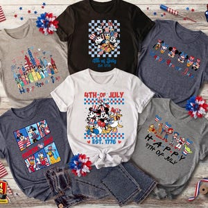 Puede incluir: Colecci&oacute;n de camisetas gr&aacute;ficas con temas patri&oacute;ticos. Los dise&ntilde;os incluyen personajes de Disney, fuegos artificiales y los textos "4th of July" y "Happy 4th of July". Las camisetas son de varios colores, incluyendo gris, blanco y azul marino.