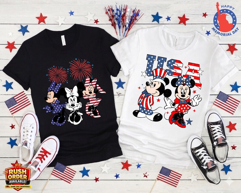 Puede incluir: Dos camisetas, una negra y otra blanca, con dise&ntilde;os patri&oacute;ticos. La camiseta negra tiene a Minnie Mouse y fuegos artificiales. La camiseta blanca muestra a Mickey y Minnie Mouse con el texto "USA". Banderas americanas y estrellas decoran el conjunto.