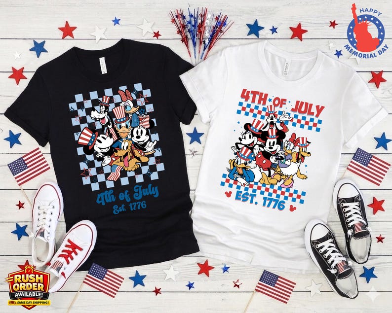Puede incluir: Dos camisetas, una negra y otra blanca, con personajes de dibujos animados con atuendos patri&oacute;ticos. Las camisetas muestran "4th of July Est. 1776". Banderas americanas y estrellas decoran las camisetas, junto con pares de zapatillas.