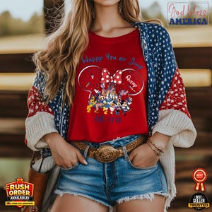 以下が含まれることがあります： ディズニーのキャラクター、ミニーマウスのリボン、そして「Happy 4th of July Avery Est. 1776」の文字が入ったグラフィックが特徴の赤いTシャツ。 赤、白、青のアメリカ国旗のデザインのカーディガンを着ています。