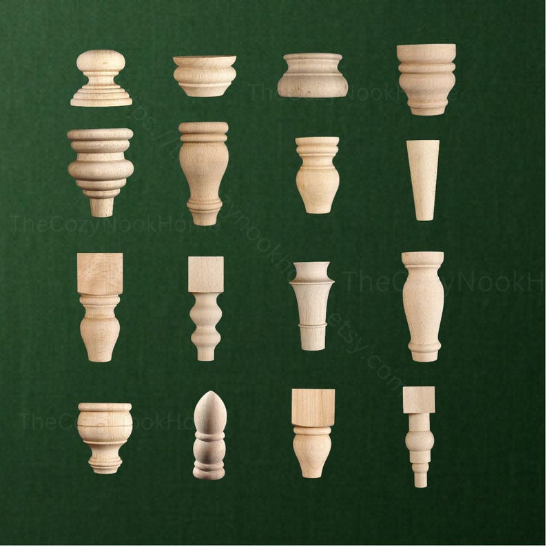 May include: A collection of sixteen unfinished light-colored wooden furniture feet and knobs arranged in a grid. The pieces feature various turned, tapered, and square-topped designs, showcasing natural wood grain textures and smooth, rounded profiles.