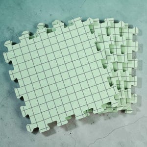 May include: Interlocking foam floor tiles in a light green color with a grid pattern. The tiles have a puzzle-piece edge for easy assembly. The tiles are designed for use in playrooms, gyms, or other areas where a soft, cushioned surface is desired.