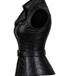 May include: Black leather vest with a collared neckline, shoulder accents, and a belted waist. The vest features a zipper closure and decorative buttons. The design is form-fitting and tailored, suitable for various styles.