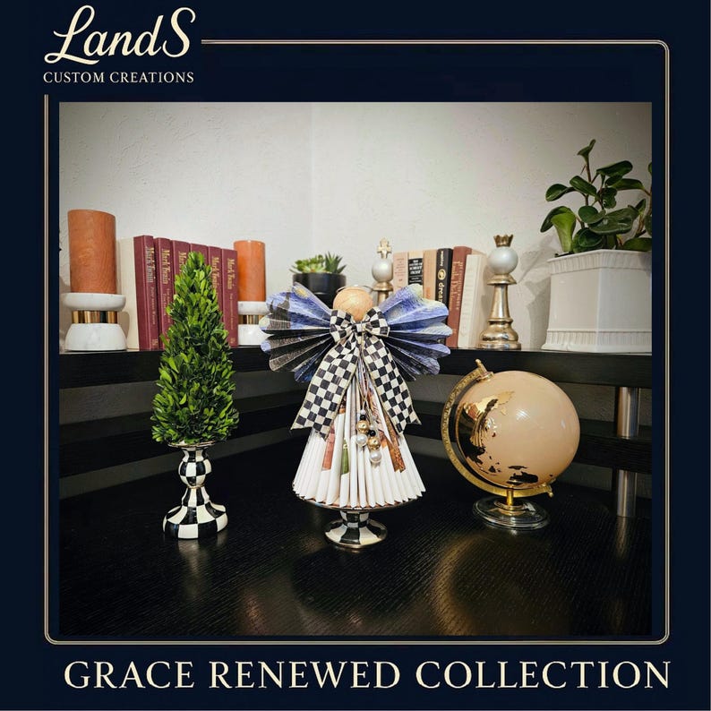 Puede incluir: Una figura decorativa de &aacute;ngel con un lazo y alas a cuadros blancos y negros, un peque&ntilde;o &aacute;rbol verde y un globo dorado sobre una superficie negra. El texto "Grace Renewed Collection" est&aacute; en la parte inferior.