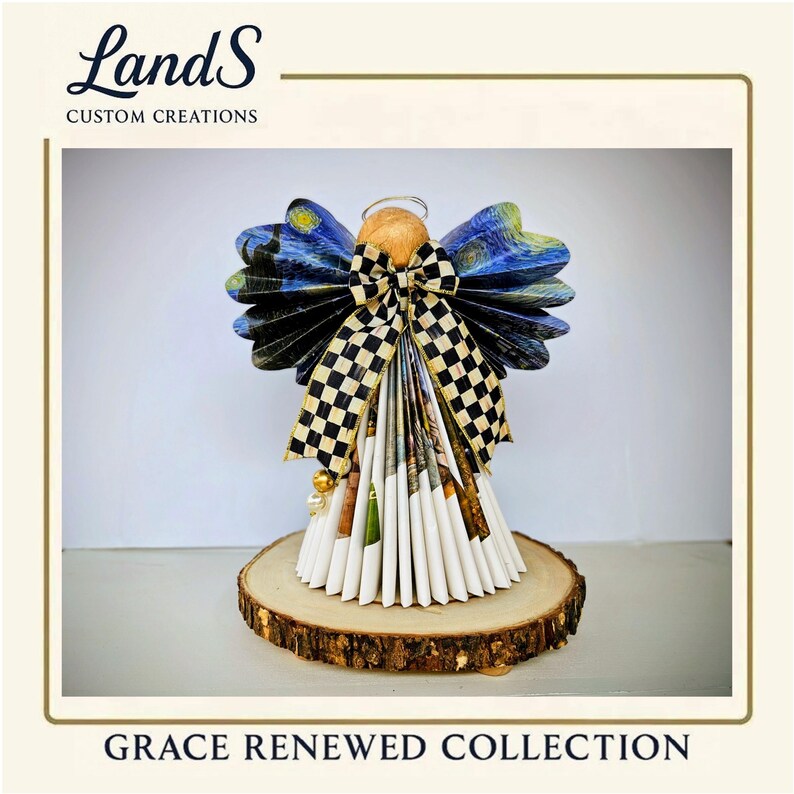 Puede incluir: Figura de &aacute;ngel artesanal con alas estampadas en azul y amarillo, un lazo a cuadros blanco y negro y una falda de papel blanca. El &aacute;ngel est&aacute; montado sobre una base de rodaja de madera. El texto "LandS Custom Creations" y "Grace Renewed Collection" son visibles.