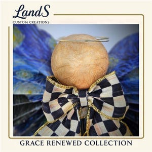 Puede incluir: Figura de &aacute;ngel con una cabeza esf&eacute;rica texturizada y un halo dorado. La pajarita del &aacute;ngel presenta un patr&oacute;n de cuadros blancos y negros con ribete dorado. Las alas son azules con un patr&oacute;n arremolinado. El texto "Grace Renewed Collection" est&aacute; en la parte inferior.