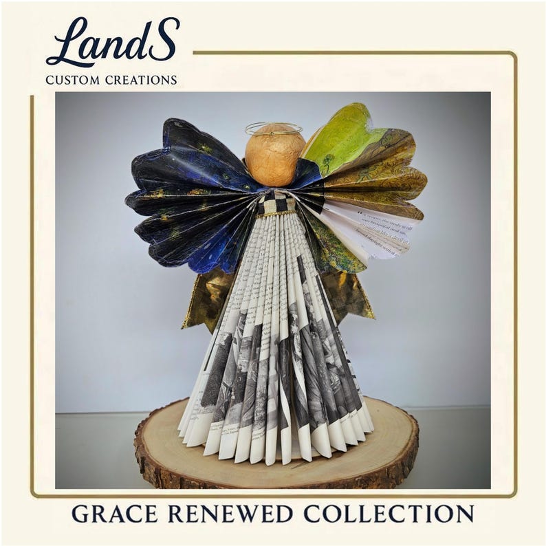 Puede incluir: Una escultura de &aacute;ngel hecha a mano con papel plegado, con una cabeza beige, un halo dorado y alas con detalles azules, verdes y dorados. El cuerpo del &aacute;ngel est&aacute; hecho de papel plegado en blanco y negro. La base es una rodaja de madera. El texto "Grace Renewed Collection".