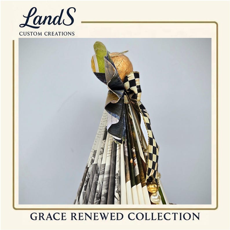 Puede incluir: Una pantalla de l&aacute;mpara decorativa de la colecci&oacute;n Grace Renewed. La pantalla presenta una esfera dorada en la parte superior, un lazo a cuadros blanco y negro y un dise&ntilde;o plisado con im&aacute;genes en blanco y negro. La marca "LandS Custom Creations" es visible.