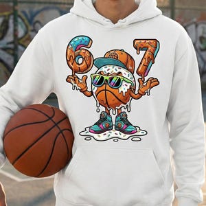May include: White hoodie featuring a basketball-themed graphic. The graphic depicts a basketball character with sunglasses, a hat, and sneakers, with the numbers "6" and "7" made of donuts. A basketball is held in the person's hand.