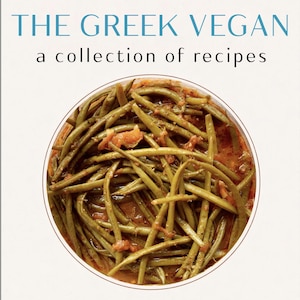 May include: A cookbook titled "THE GREEK VEGAN" with the subtitle "a collection of recipes." The image features a close-up of a dish of green beans in a tomato-based sauce, presented in a white bowl with a brown rim.