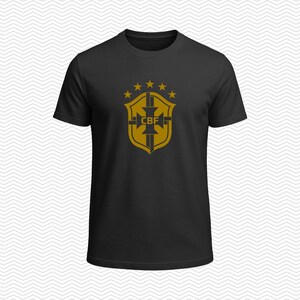 May include: A black short-sleeved t-shirt featuring a gold-colored graphic on the chest. The graphic displays a shield emblem with the letters CBF in the center, topped by five small stars arranged in an arc above the shield design.