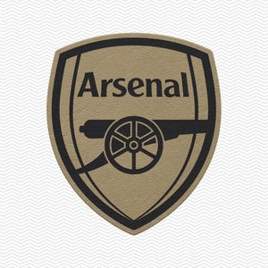 May include: A shield-shaped patch featuring the Arsenal football club logo in a tan and black color scheme. The design includes the word Arsenal in black text above a black cannon graphic, all set against a textured tan background.