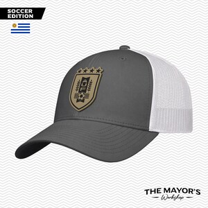 May include: Gray baseball cap with a white mesh back and a curved brim. The cap features a gold patch with a soccer emblem and the text "SOCCER EDITION". The Mayor's Workshop logo is at the bottom.