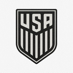 May include: A black and white USA shield-shaped emblem. The emblem features the letters "USA" in white, set against a black background with vertical white stripes. The shield has a textured appearance.