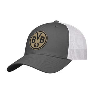 May include: A charcoal gray baseball cap with a white mesh back and a circular patch on the front. The patch features a tan background with a black border and the black text BVB 09 centered within the circle. The cap has a curved brim.
