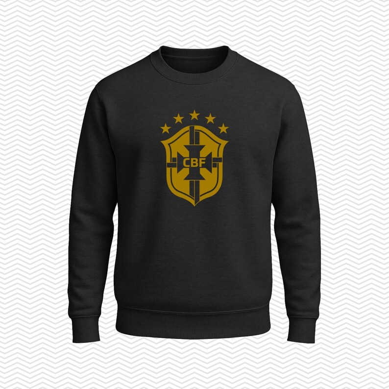 May include: A black long-sleeve crewneck sweatshirt featuring a gold-colored graphic on the chest. The graphic displays a shield emblem with the letters CBF in the center, topped by five small stars arranged in a horizontal arc above the shield.