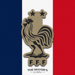 May include: A tan-colored emblem featuring a black rooster silhouette and two stars above it, with the letters F.F.F. below. The text THE MAYOR'S Workshop is printed at the bottom, all set against a background of blue, white, and red vertical stripes.
