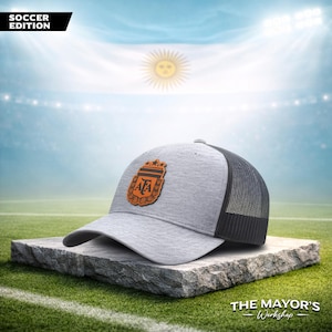 May include: Gray and black trucker hat with the Argentina national team logo. The hat features a mesh back and a curved brim. The text "SOCCER EDITION" is in the upper left corner.