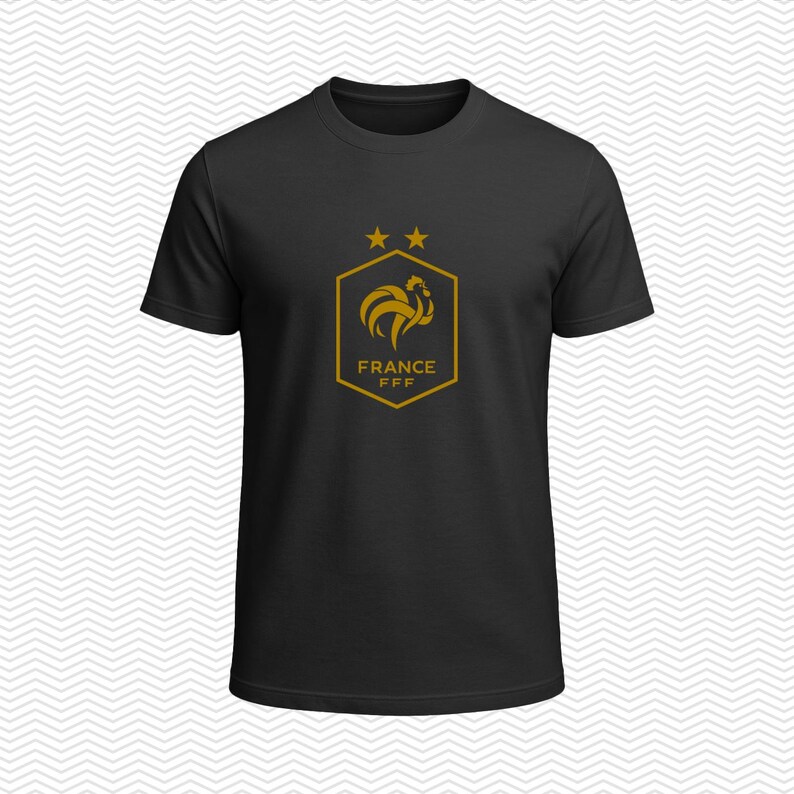 Puede incluir: Una camiseta negra de manga corta con un gr&aacute;fico de color dorado en el pecho. El dise&ntilde;o incluye un emblema hexagonal con un gallo estilizado, dos estrellas sobre el hex&aacute;gono y el texto FRANCE FFF impreso dentro del emblema.
