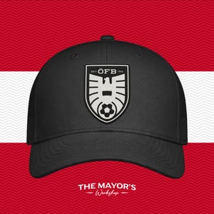 May include: A black baseball cap featuring a centered shield-shaped patch. The patch displays a white eagle emblem above a soccer ball, with the text "SEIT ÖFB 1904" arched at the top. The cap has a structured crown and a curved brim.