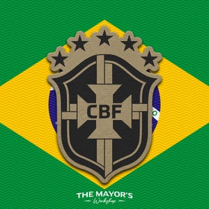 May include: A tan and black shield-shaped emblem featuring the letters CBF at the center, topped with five black stars. The emblem is layered over a green, yellow, and blue Brazilian flag background with the text THE MAYOR'S Workshop at the bottom.