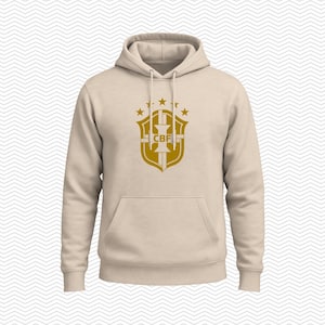 May include: A beige hooded sweatshirt featuring a gold-colored graphic on the chest. The graphic displays a shield emblem with the letters CBF in the center, topped with five stars arranged in an arc. The hoodie includes a front kangaroo pocket.