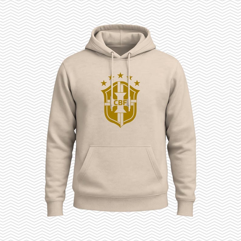 May include: A beige hooded sweatshirt featuring a gold-colored graphic on the chest. The graphic displays a shield emblem with the letters CBF in the center, topped with five stars arranged in an arc. The hoodie includes a front kangaroo pocket.