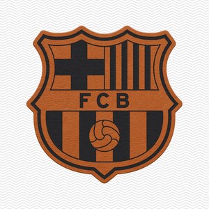 May include: A shield-shaped emblem featuring the FCB logo in a burnt orange and black color scheme. The design includes a cross, vertical stripes, and a soccer ball graphic, with the letters FCB centered horizontally across the middle section.