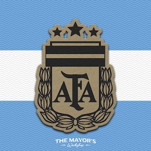 May include: A tan-colored emblem featuring the black AFA acronym, three black stars at the top, and a laurel wreath border. The design is centered on a background of horizontal light blue and white chevron-patterned stripes with text below.