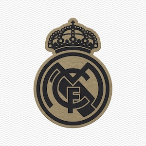 May include: A circular patch featuring the Real Madrid football club logo in black and tan. The design includes a stylized crown at the top and the intertwined letters MCF in the center, all set against a textured tan background with black borders.