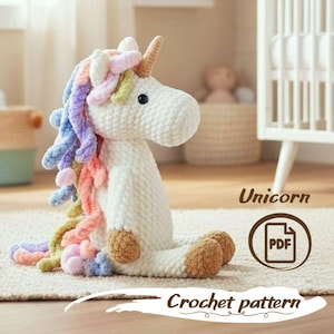 Può includere: Un unicorno bianco all'uncinetto con criniera e coda multicolore, seduto su un tappeto. L'unicorno ha un corno e zoccoli marroni. Il testo sull'immagine recita "Unicorn" e "Crochet pattern".