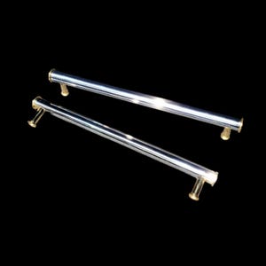 May include: Two polished chrome cabinet pulls with gold-toned end caps are displayed against a black background. The pulls are straight, cylindrical bars, ideal for drawers or doors. The hardware is approximately 12 inches long.