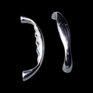 Può includere: Due maniglie per porte cromate. Una ha un design curvo con rientranze a forma di onda per l'impugnatura. L'altra è un design liscio e curvo. Entrambe sono riflettenti e sembrano essere in metallo.