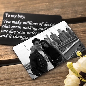 May include: A black and white photo card featuring a couple posing on a bridge with a city skyline in the background. A second black card with white text that reads "To my boy, You make millions of decisions that mean nothing and one day your order and it changes."