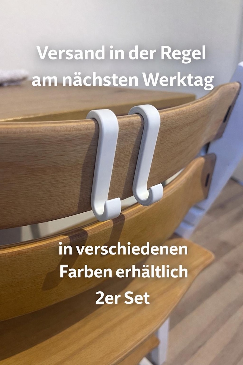 May include: Two white, curved hooks designed to attach to a wooden chair. The hooks are shown attached to the chair's backrest. Text in the image says "Versand in der Regel am n&auml;chsten Werktag" and "in verschiedenen Farben erh&auml;ltlich 2er Set."