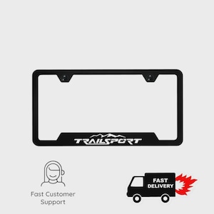 Puede incluir: Marco de matrícula negro con la palabra "TRAILSPORT" en blanco. El marco tiene forma rectangular con esquinas redondeadas y dos orificios de montaje en la parte superior. La parte inferior del marco tiene una sección elevada con el nombre de la marca.